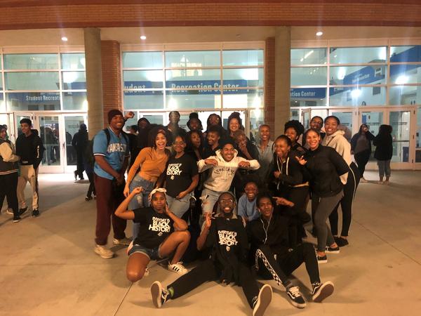 A large group of students gather for a group photo outside the Student Recreation Center at UCR